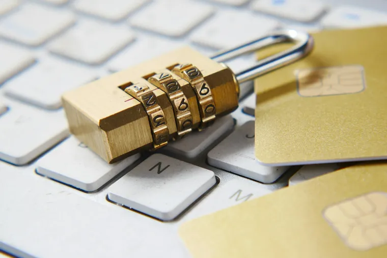 Cadenas à code doré posé sur un clavier d'ordinateur blanc